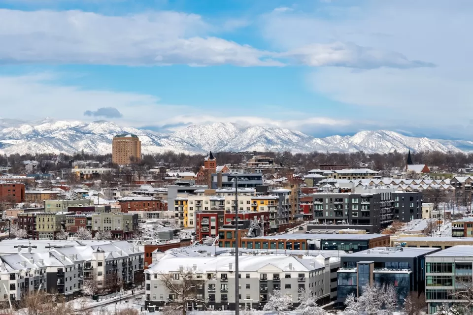 View of snowy buildings and mountains in background in Denver, Colorado.